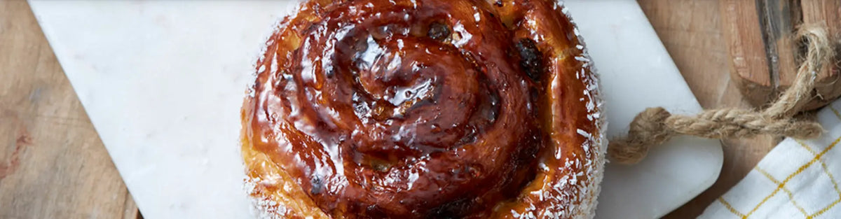 Close-up of glazed pain aux raisins swirl showing lacquered finish and flaky layers