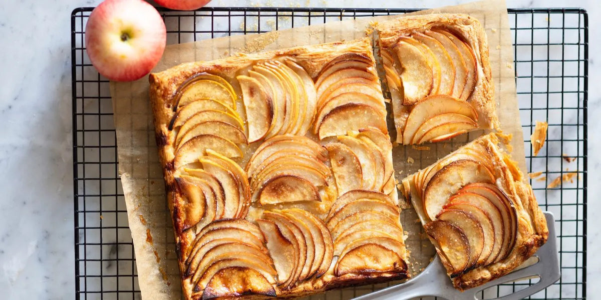 Apple tart slab sliced cleanly and styled on parchment with natural light, showcasing food styling that helps improve bakery business visuals