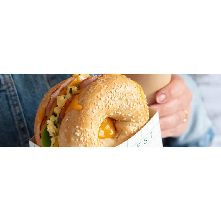 Sesame bagel breakfast sandwich with cheddar, egg and bacon served café-style
