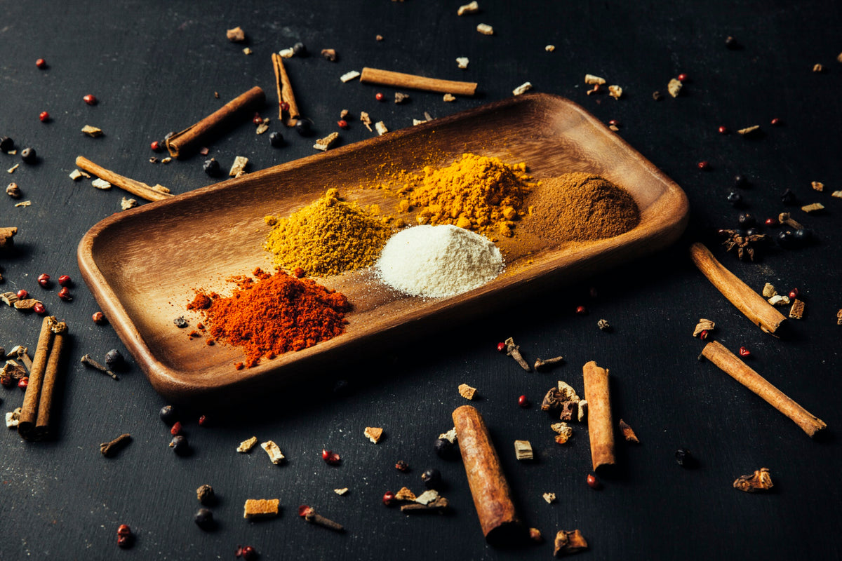 A wooden tray with colourful spices including cinnamon, nutmeg, ginger and cloves, perfect for enhancing Delifrance carrot cake recipe
