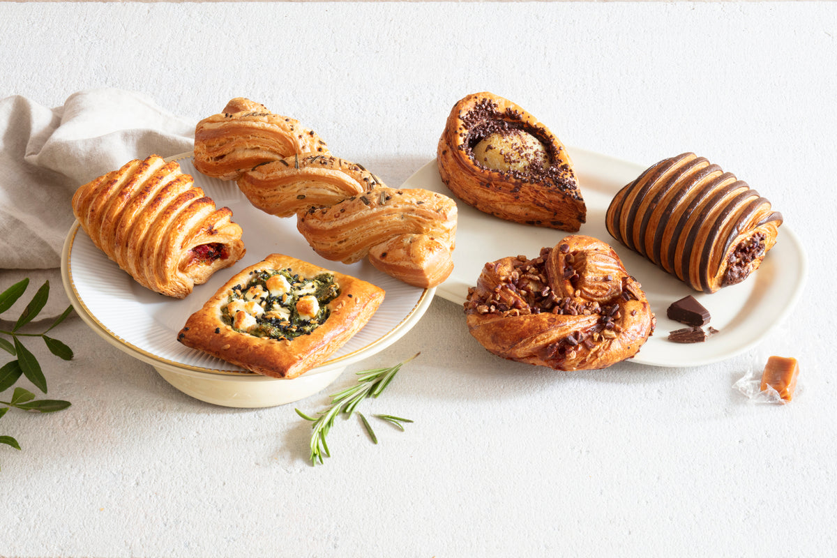 Assorted Délifrance Extraordinary range viennoiserie, including chocolate hazelnut roll and other hand-finished pastries, beautifully arranged on plates