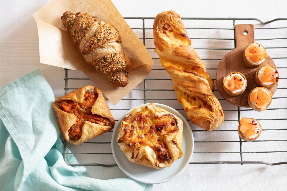 Freshly baked Delifrance pastries including croissants and savoury bakes on cooling rack and serving plate