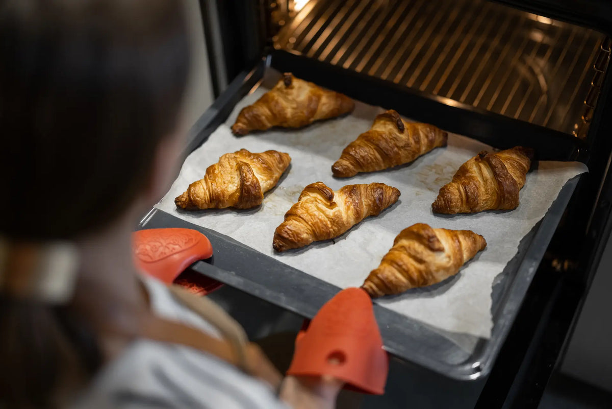 Close-up showing the flaky layers of a Délifrance ham and cheese croissant with melted cheese filling on a plate