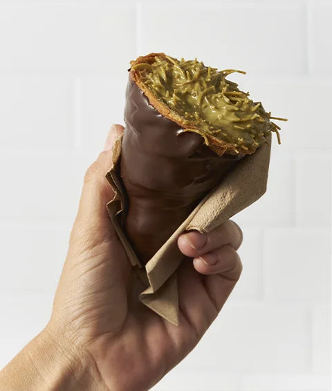 Hand holding a filled pastry cone showing food personalisation