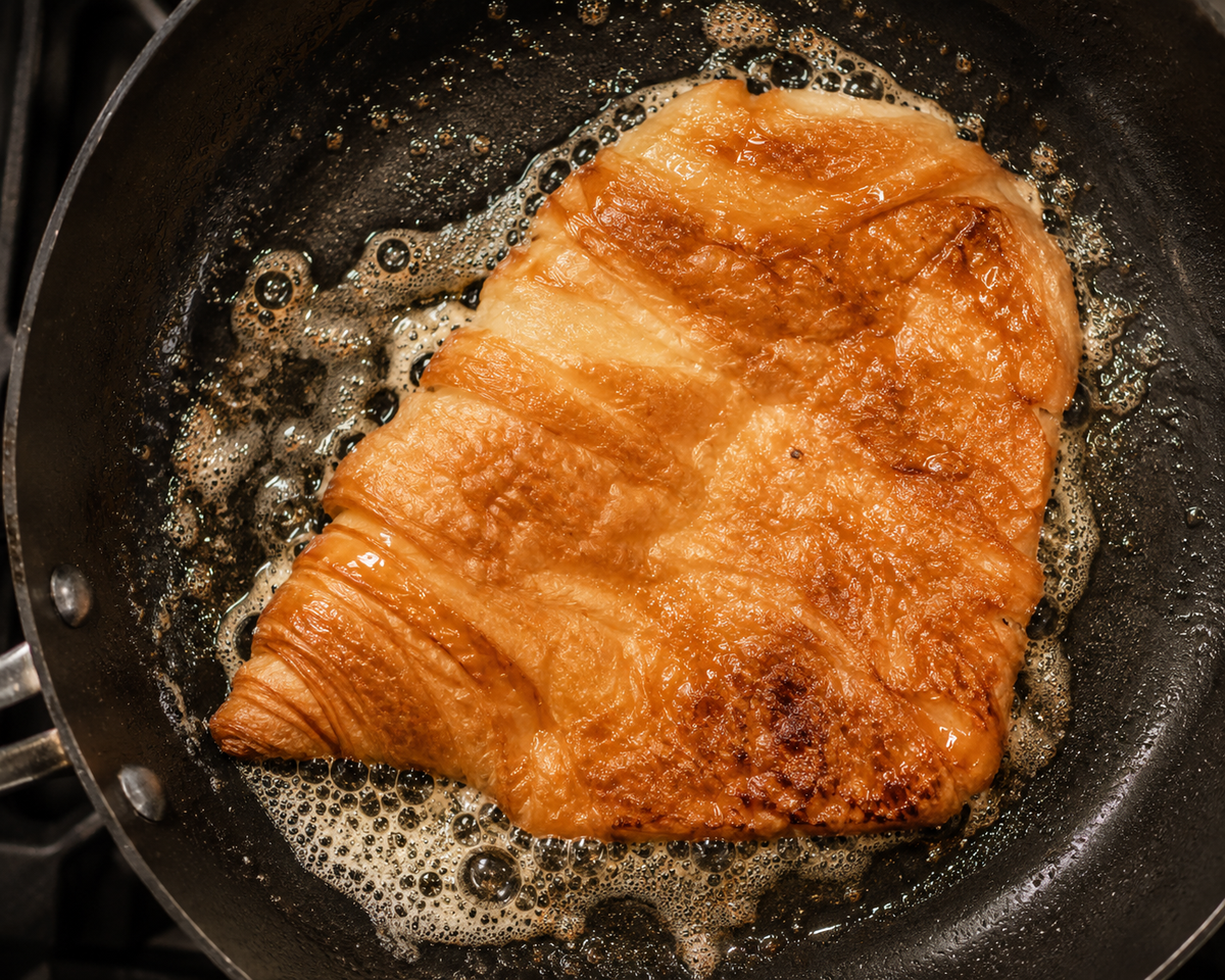 A croissant flattened and pan-fried until golden for a smashed croissant dessert.